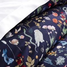 the bedding is made up with colorful flowers and birds on it's navy blue sheets