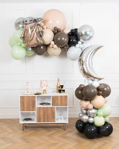 balloon arch with moon and stars on it in front of a white wall filled with balloons