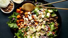 a salad with lettuce, chickpeas, and dressing on a black plate