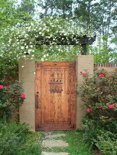 a wooden door surrounded by flowers and greenery