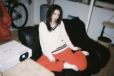 a woman sitting on a black couch in front of a projector and a table