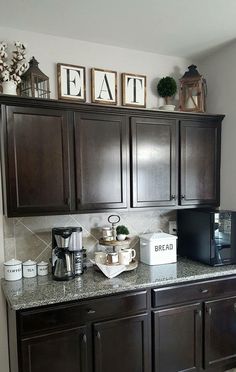 a kitchen with dark wood cabinets and white appliances on the counter top, along with pictures above it