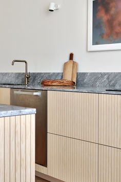 a kitchen with marble counter tops and wooden cabinets in the background, along with a painting on the wall