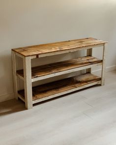 a wooden table sitting on top of a hard wood floor next to a white wall