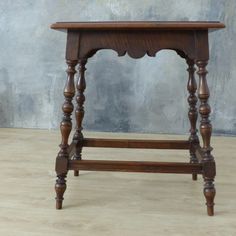 an old wooden table sitting on top of a hard wood floor next to a wall