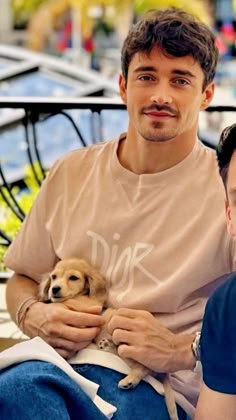 two men sitting next to each other on a bench with a dog in their lap