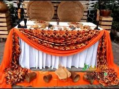 an orange and white table cloth on top of a wooden bench with two wicker chairs