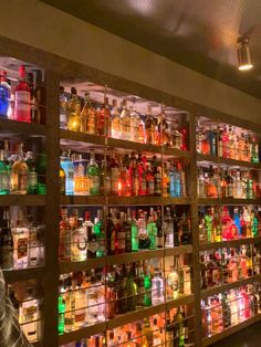 a man standing in front of a wall filled with bottles