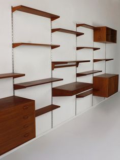 the shelves are lined up against the wall with wooden drawers on each side and white walls behind them