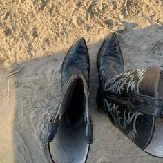 a pair of black shoes sitting on top of a sandy beach