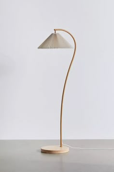 a floor lamp with a wooden base and a white shade on the top, sitting on a gray surface