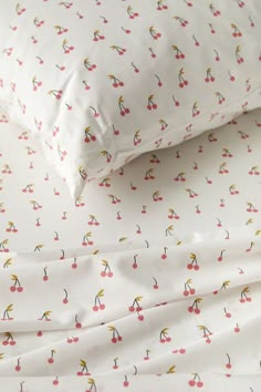 two pillows with cherries on them sitting next to each other in front of a pillow case