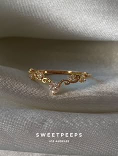 a gold ring with two small diamonds on the top and bottom, sitting on a white cloth