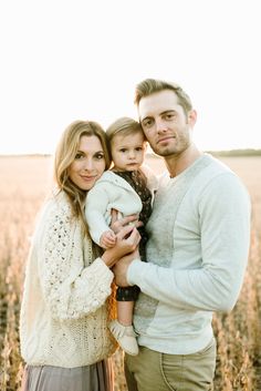 a man and woman holding a baby in a field