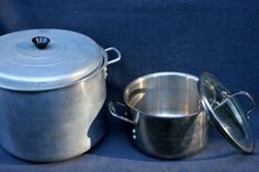 two pots and one pan are sitting next to each other on a blue cloth background