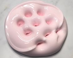 a close up of a pink object on a white surface with holes in the middle