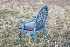 an old blue chair sitting in the middle of a grassy field with no one around it