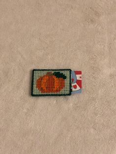 an orange beaded pumpkin sitting on top of a white carpet next to a red and white flag