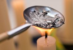 a close up of a metal spoon with some food on it's side and a candle in the background