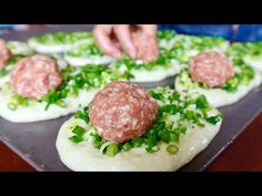 a tray filled with meatballs covered in sauce and green onions on top of it