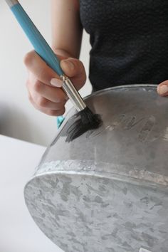 a woman holding a brush in her right hand and cleaning the bottom of a bucket