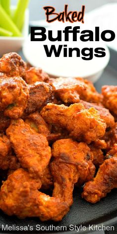 baked buffalo wings on a black plate with green onions and ranch dressing in the background