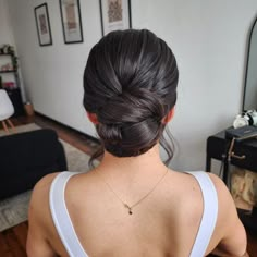 a woman with her back to the camera, wearing a white tank top and gold necklace