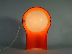 an orange table lamp sitting on top of a white counter next to a gray wall