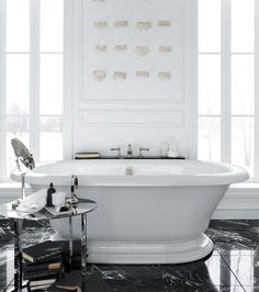 a white bath tub sitting next to two windows in a room with black marble flooring