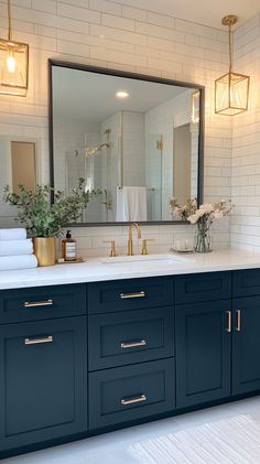 a bathroom with blue cabinets and white tile on the walls, along with a gold faucet