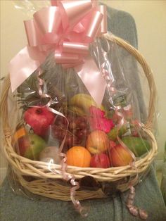 a basket filled with fruit sitting on top of a chair next to a pink bow