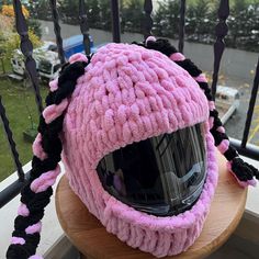 a pink knitted hat sitting on top of a wooden table