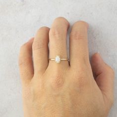 a person's hand with a gold ring on their left and a white diamond in the middle