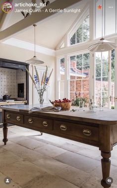 a kitchen with an island table in the middle of it and lots of windows on both sides