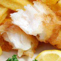 fish and chips on a plate with lemon wedges