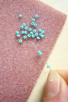 someone is making something with beads on a piece of felt