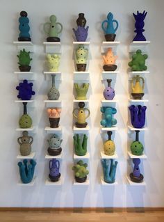 a wall mounted shelf filled with different types of vases and cactuses on top of white shelves