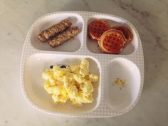 a plate with eggs, sausages and waffles on it sitting on a table