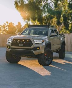 a toyota truck parked in a parking lot with the sun shining on it's tires