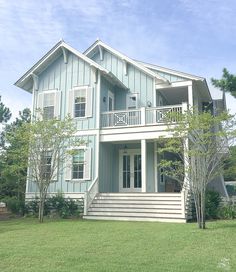 a large blue house sitting on top of a lush green field