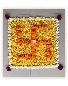 an arrangement of flowers arranged in the shape of a square with a candle on top