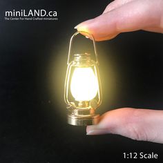 a hand holding a light that is on top of a black surface with the words miniland ca below it