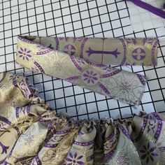 two pieces of purple and gold fabric sitting next to each other