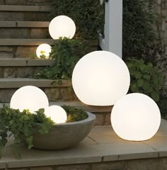 three white lights sitting on top of steps next to a bowl filled with green plants