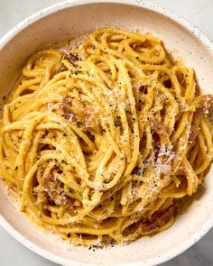 a white bowl filled with pasta covered in parmesan cheese