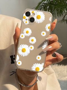 a woman holding up her phone case with daisies on it