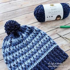 a crocheted beanie hat next to scissors and yarn on a wooden table