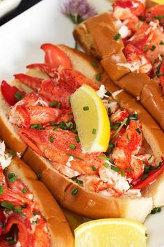 lobster sandwiches with lemon wedges and garnish on a white plate, ready to be eaten