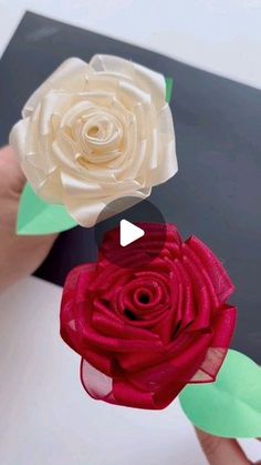 two paper flowers being held by someone's hands