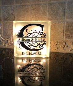 the illuminated sign is in front of a brick wall with an elegant monogrammed design